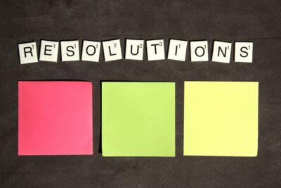 'Resolutions' in letter tiles, with three coloured sticky notes beneath them. Photo: Pexels.com