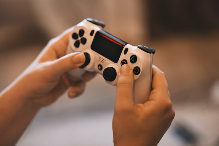 Hands hold a white Sony ps4 control. Photo by EVG Kowalievska on Pexels