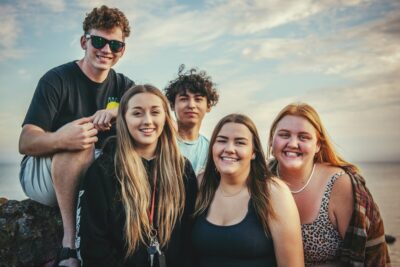A group of teens smile at the camera. By Tim Mossholder on Pexels