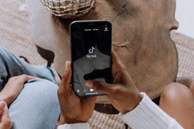 Looking down at a phone in a woman's hand that shows tiktok. By cottonbro studio on pexels