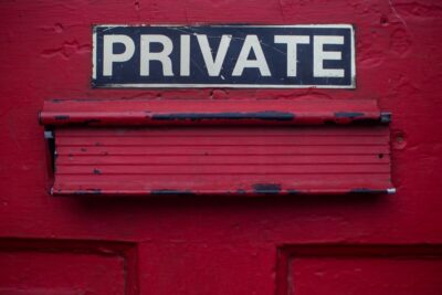 Private sign above a letterbox on a red door. Photo: Dayne Topkin on Unsplash.
