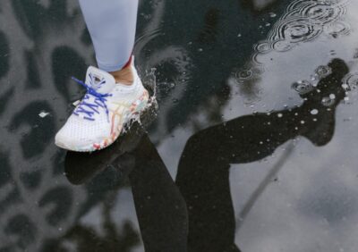 A runner's leg and their reflection in a puddle. By Cottonbro on Pexels
