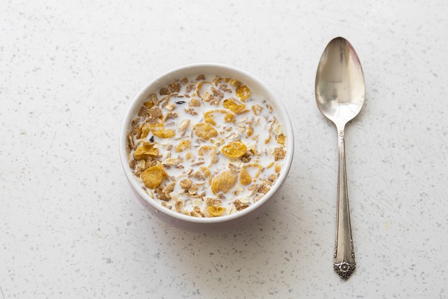 A bowl of cereal with a spoon lying next to it.