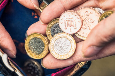A handful of coins going into a purse. By Istock