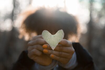 A woman holds out a white heart shaped leaf