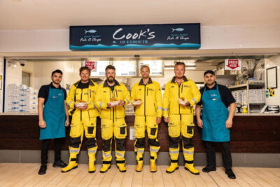 RNLI lifeboat volunteers with staff at a Cook's Fish & Chips shop at Havens