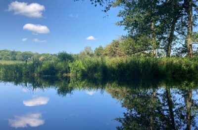 Two small white clouds reflected in a river. Copyright Melanie May