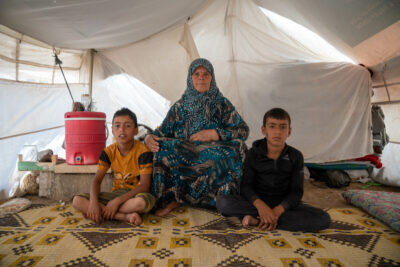 Shahinaz and her grandsons sit in their tent at a camp in north-west Syria on 22 June 2023. Credit: Arete, Arete