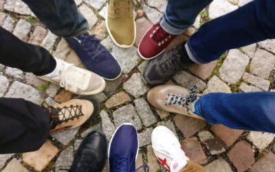 A group of feet in trainers and walking boots make a circle. By Ingo Jones on Pexels