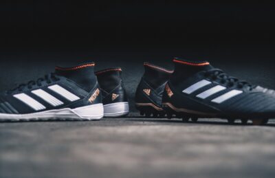 Two pairs of football boots, back to back. By Fachry Zella Devandra on unsplash