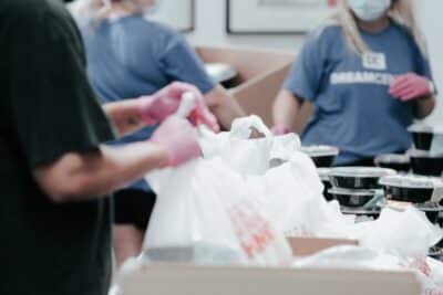 Volunteers at a foodbank sorting plastic bags of food. Photo: Joel Muniz, Unsplash.com