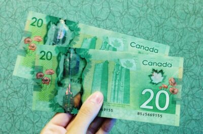 A woman's hand holds green Canadian dollars. By Michelle Spollen on Unsplash