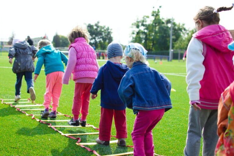 A line of children navigating a rope ladder on a field. By Lukas on pexels
