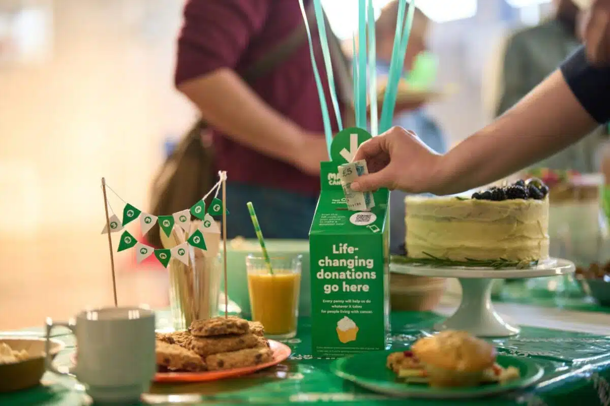 Macmillan Coffee Morning – a hand puts £5 in a donation box