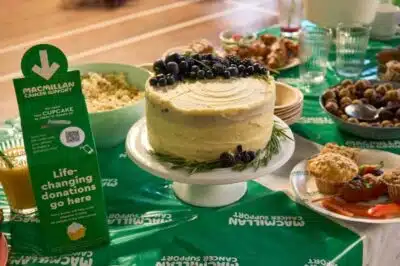 A donation box for Macmillan Coffee Morning with a QR code, on a table of cakes