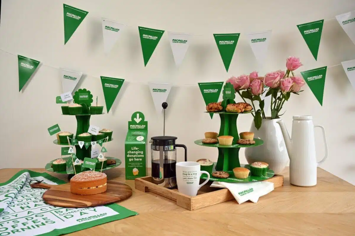 Macmillan Coffee Morning bunting and donation box with a table with a coffee pot and mug, an a cake