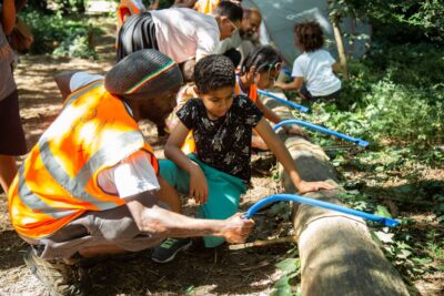 Children and adults sawing wood at South London-based forest school and environmental charity Nature Vibezzz, which received a £30,000 grant from City Bridge Foundation's small grants programme