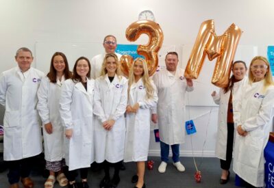 people in while CRUK lab coats hold up balloons spelling 3million - the amount Bellway has so far raised for the charity