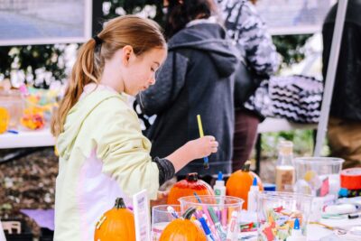 A girl paints a pumpkin. By Rosemary Ketchum on pexels