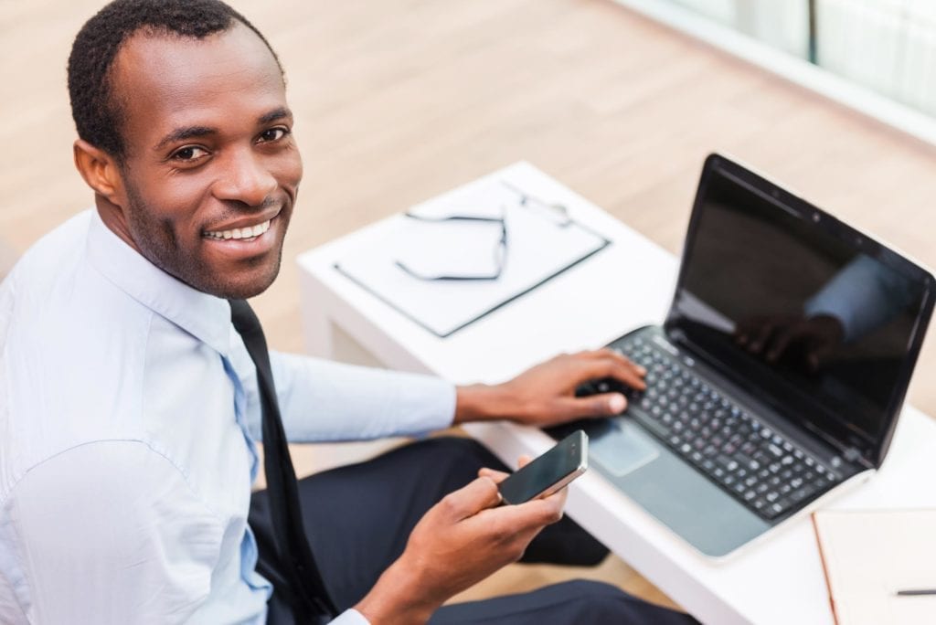 Male black worker using laptop and phone
