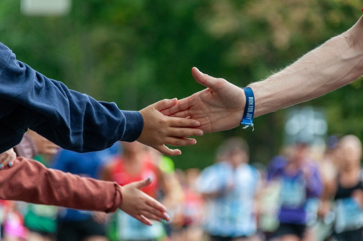 a racer's hand reaches out to touch a child's hand during a race. By 117O8734 on pixabay