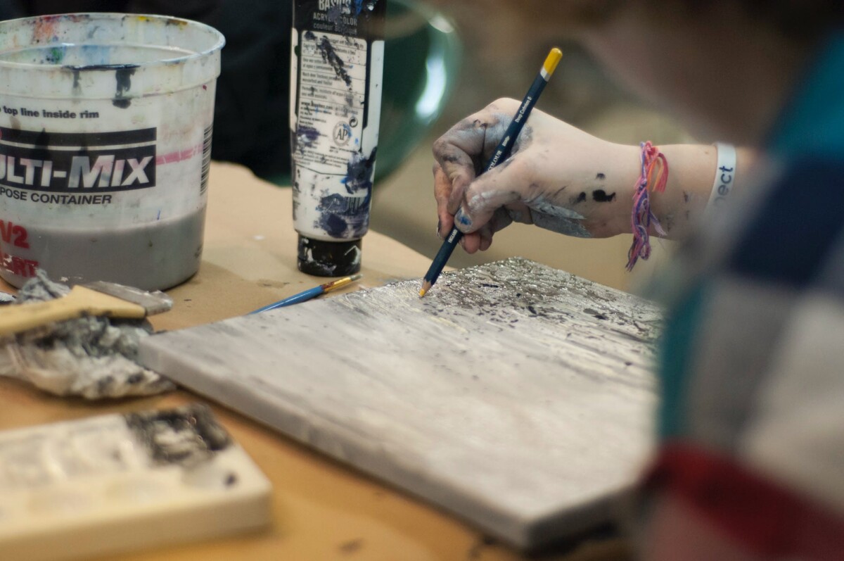 An artist draws on a board. By Alicia Zinn on Pexels