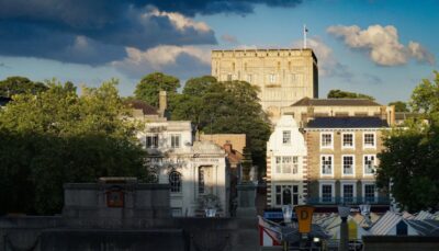 A scene looking across a street with trees and old buildings to Norwich castle. By Suzy Hazelwood on Pexels