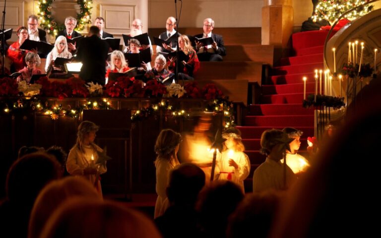People singing at Christmas in a candle lit church. By Blue Ox Studios on pexels