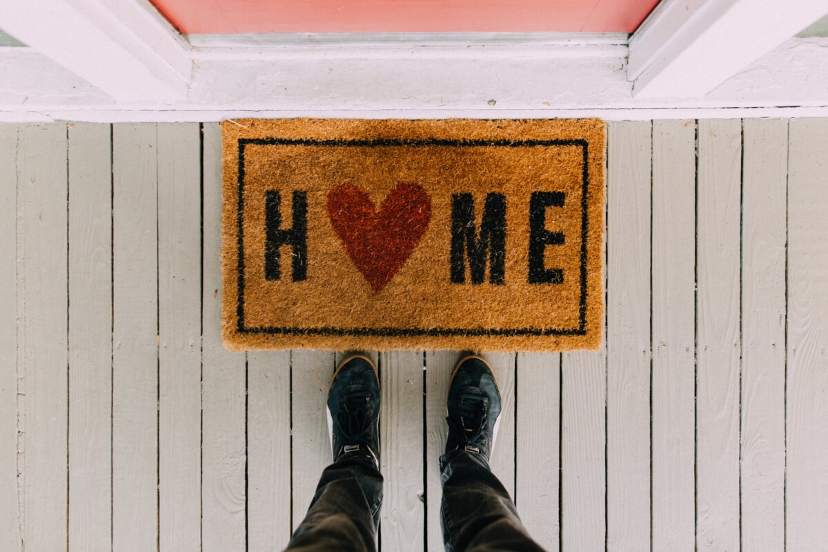 'Home' on a doormat, with the 'O' replaced by a red heart shape.