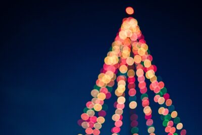 Out of focus christmas lights in a tree shape by Tim Mossholder on pexels