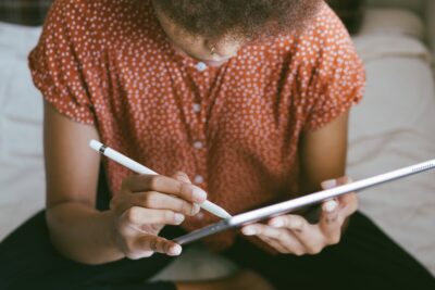 A woman looks down at a tablet that she is using with a pen. By RF Studio on pexels