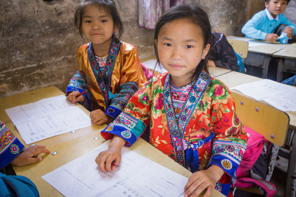 Children at desks in a school in China, supported by Couleurs de Chine.