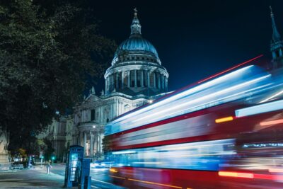 A bus streaks past St Paul's Cathedral in London at night. By Ben Kirby on Pexels