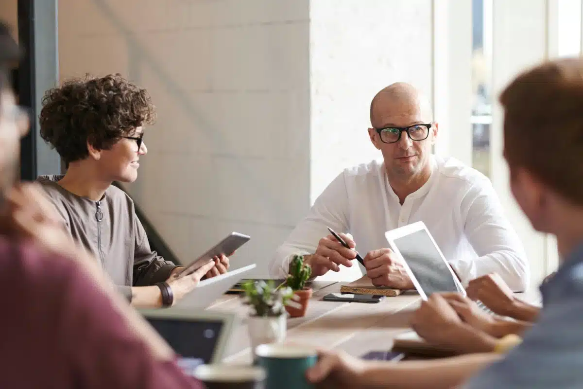 A group of people sit around a table in an office, at a meeting. By Fauxels on Pexels