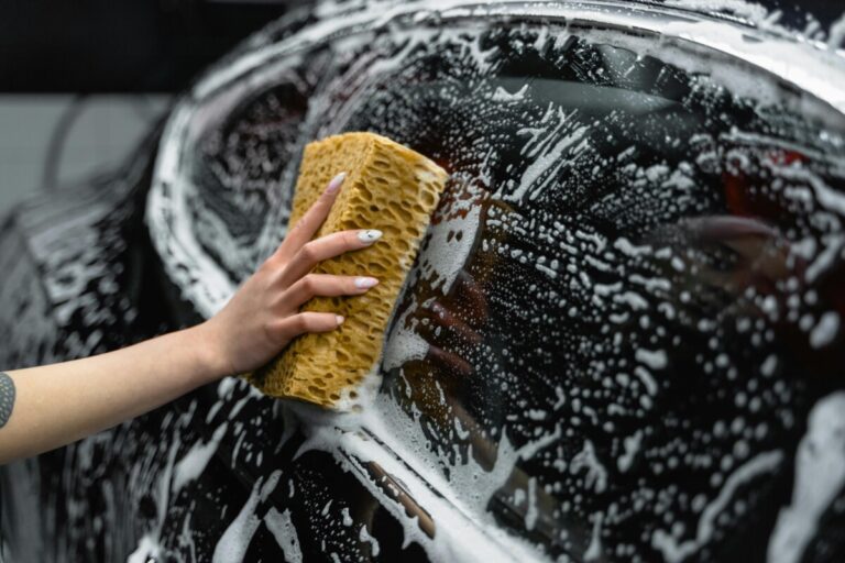A hand washes a car window with a soapy sponge. By Tima Miroschnichenko on pexels