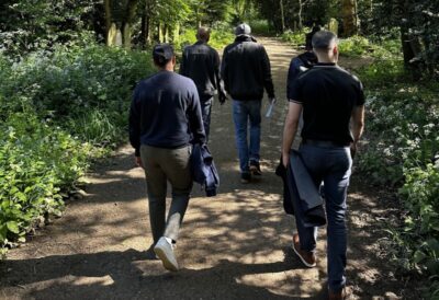 A group of men walking through a green and sunny cemetery. Credit: Mental Health Foundation / Farid Akhtar