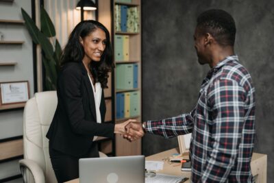 A female lawyer shakes hands with a client over a desk. By Pavel Danilyuk on Pexels