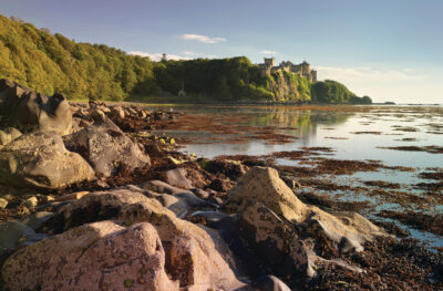 Culzean Castle with the sea and rocks, against a blue sky