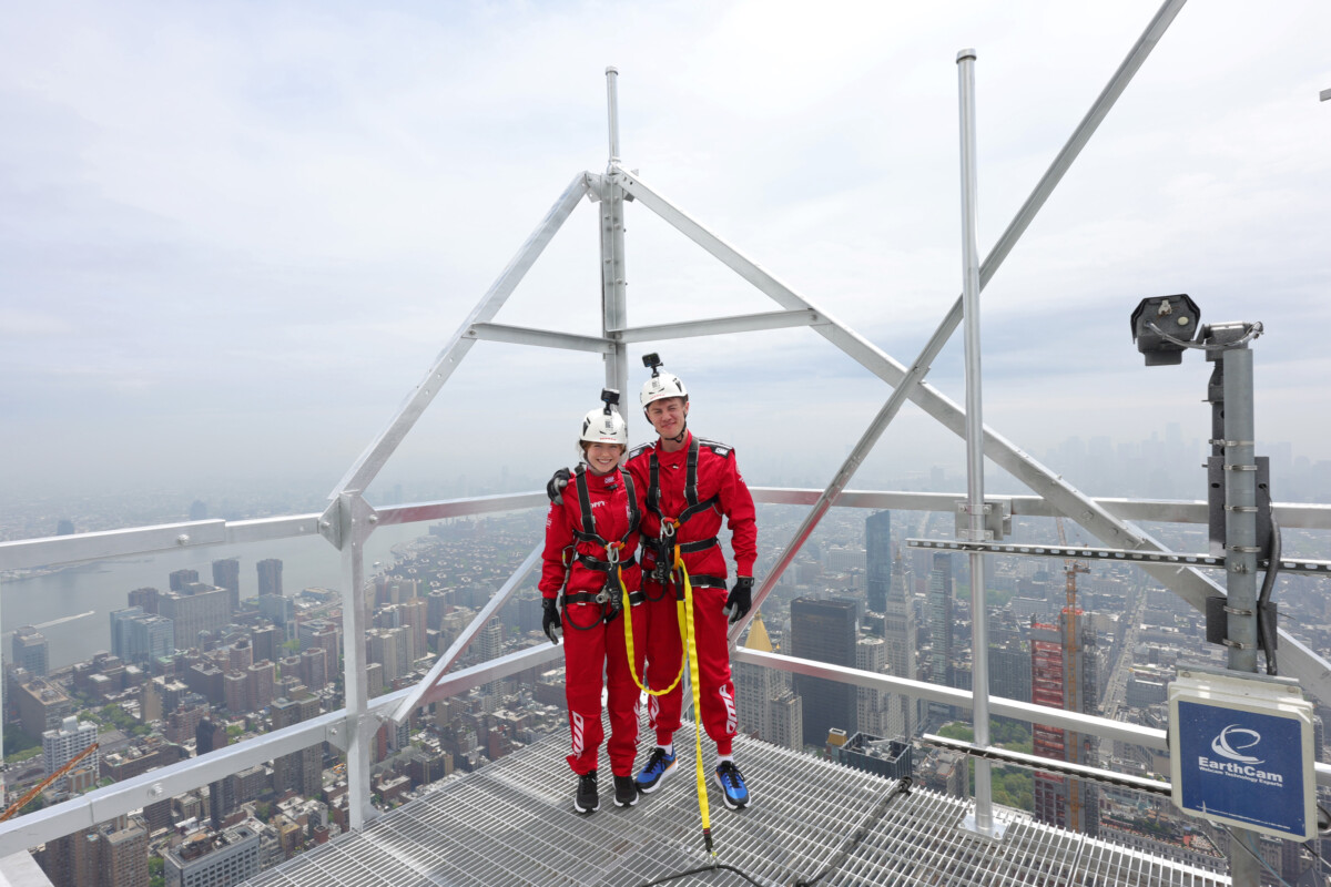 Two abseilers in red at the top of the Empire State Building.