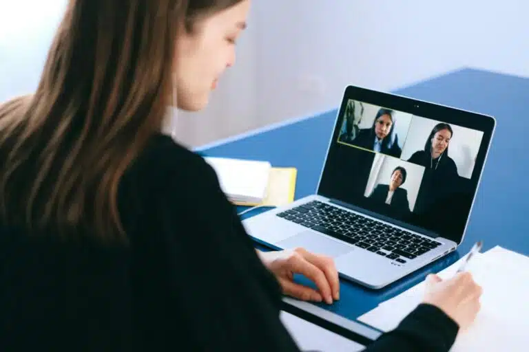 A woman on a video call looks at her laptop which shows 3 other women. By Anna Shvets on pexels