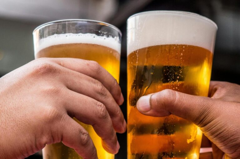 two beer glasses chink together to say 'cheers'. By Tembela Bohle on Pexels