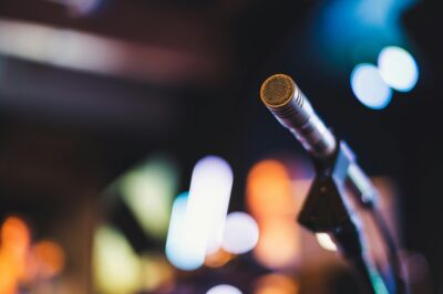 A microphone against a backdrop of blurred lights. By Brett Sayles on Pexels