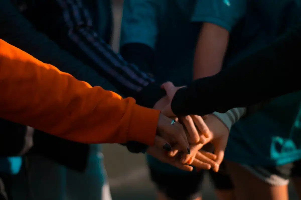 A group of people reaching out and touching hands. By Mica Asato on Pexels