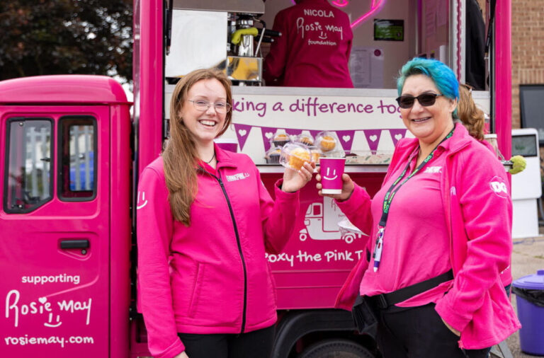 two women stand smiling in front of a pink tuk tuk celebrating and supporting the Rosie May Foundation. They are also wearing pink