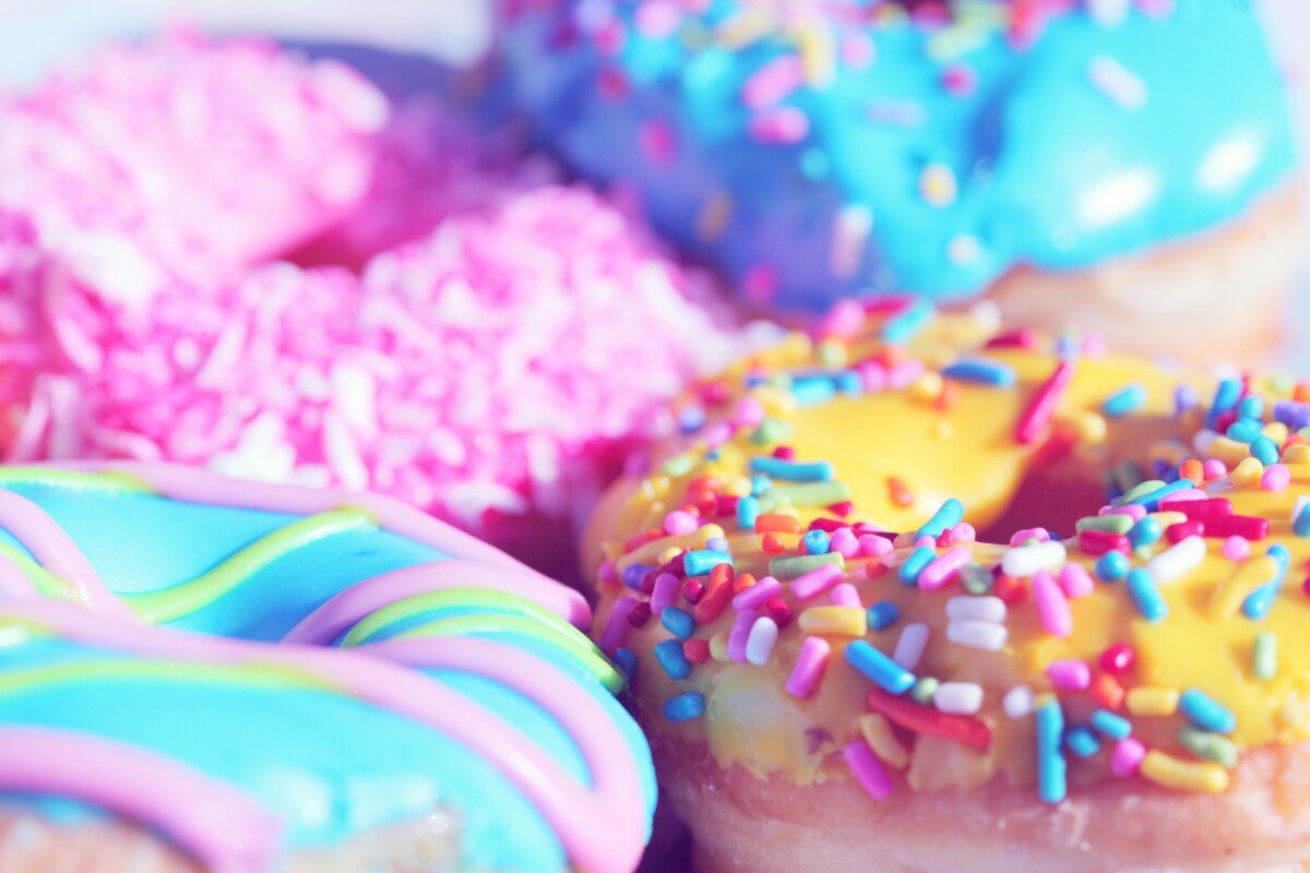 A close up of ring doughnuts with colourful icing and sprinkles. By Mccutcheon on pexels