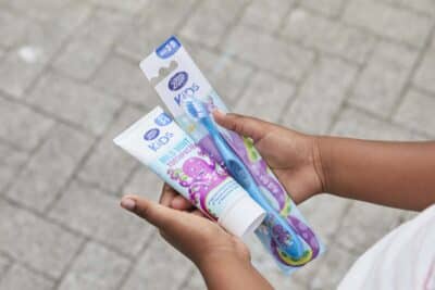 A child's hands holds a new toothbrush and tube of toothpaste - part of the Boots and The Hygiene Bank's appeal for donations of these items to help children in hygiene poverty