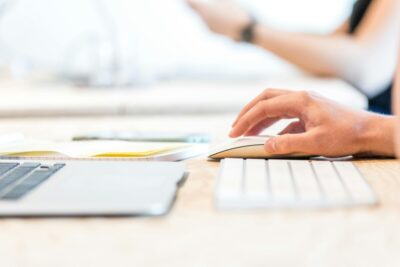 A hand moves a mouse next to their keyboard. By Lex Photography on pexels