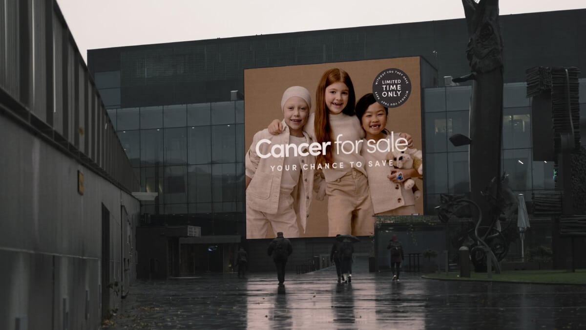 Large video display ad outside a grey office block in Finland feature what looks like a children's clothing ad, but is in fact a shocking fundraising appeal. "Cancer for sale: your chance to save", "limited time only", with three children in ecru and off white clothing hugging each other and smiling.