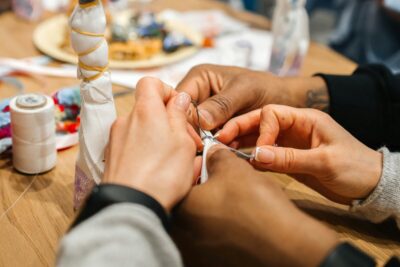 Two pairs of hands holding threads as they sew. By Mariya Klyachko on Pexels