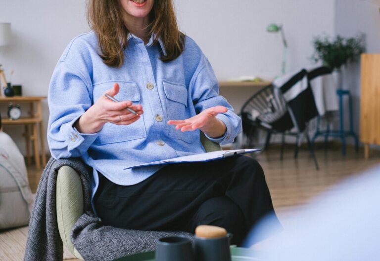 A low shot of a woman talking in a meeting with another person just off camera. By SHVETS production on pexels